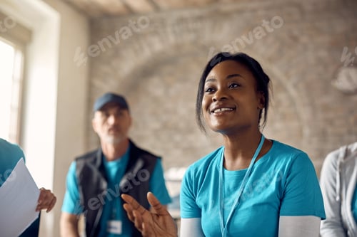 Preview: Black female donation center coordinator talking to volunteers at charity center.