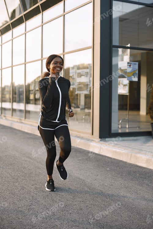 Preview: Portrait of a young fit african-american woman jogging outdoors