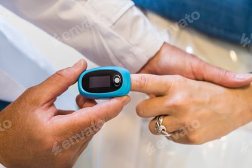 Preview: Doctor is putting a pulse oximeter in his patient's hand for measuring oxygen saturation in blood