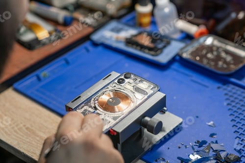 Preview: A technician carefully repairs a smartphone, focusing on battery replacement amidst various tools