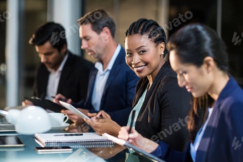 Preview: Portrait Of Businesswoman Using Digital Tablet While Colleagues Writing Notes In The Office