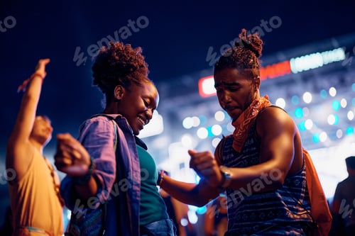 Preview: Young black couple dancing while enjoying in summer music festival at night.