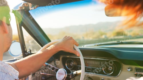 Preview: Close Up Of Couple Driving Classic Open Top Car On Road Trip Through Countryside At Sunset