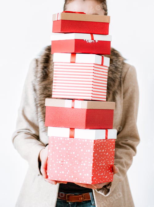 Preview: woman returning home from shopping holding pile of christmas present boxes
