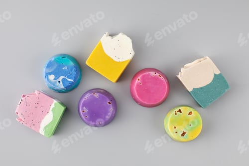 Preview: Pieces of different shapes and colors of handmade soap on a gray background. Natural cosmetics.