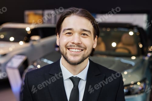 Preview: Smiling Asian Male Auto Dealer Looking at Camera at Car Dealership Center