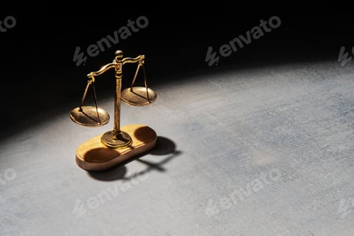 Preview: A scale of justice illuminated by a spotlight stands against a dark background.