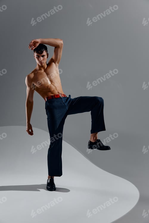 Preview: man in jeans patent shoes lifted his leg up and naked torso bodybuilder fitness