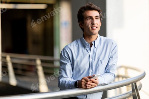 Preview: Handsome millennial entrepreneur with phone in his hands outdoor