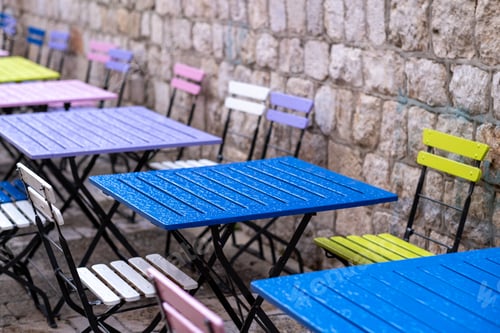 Preview: Set of colorful cafe tables with their chairs outside on a brick wall background
