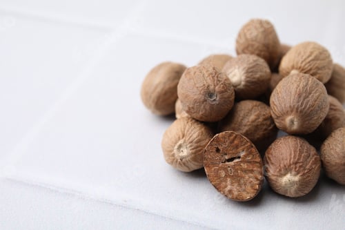 Preview: Heap of nutmegs on white table. Space for text