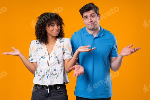 Preview: Confused Young Couple Shrugging Shoulders In Uncertainty While Looking At Camera