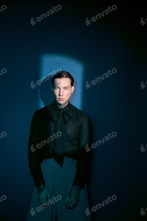 Preview: Stylish young man exudes charm and confidence under striking blue light