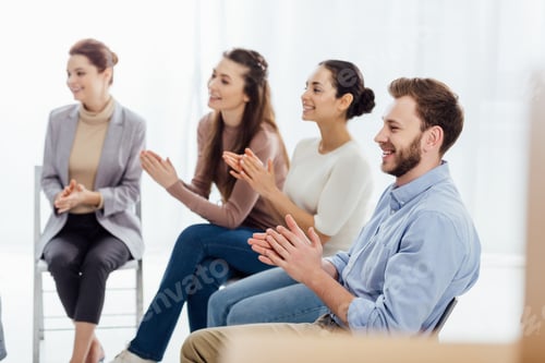 Preview: smiling group of people sitting and applauding during support group session