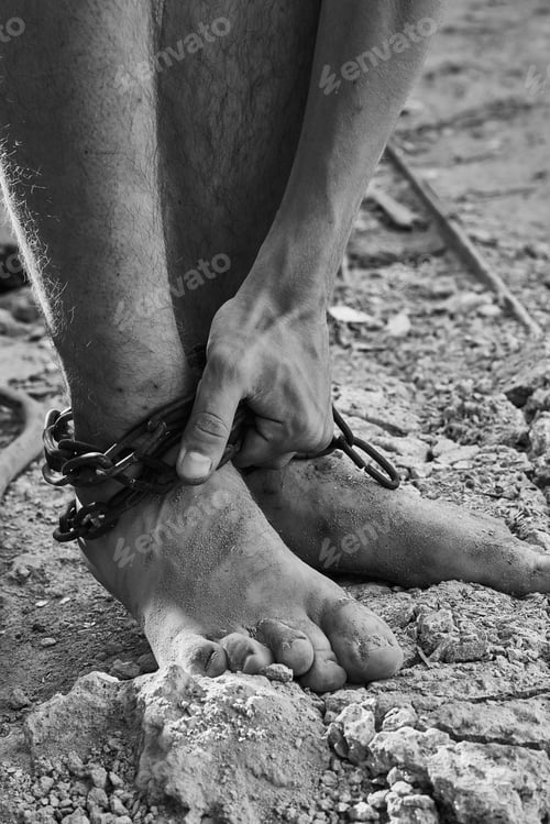 Preview: Close-up shot of barefoot legs tied up with old chain