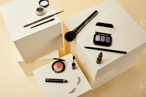 Preview: high angle view of various makeup accessories on beige cubes