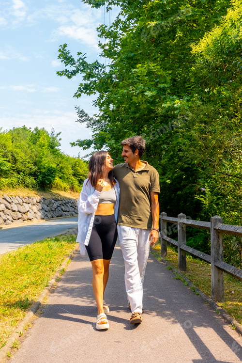 Preview: Happy couple walking on a path by the road, embracing and smiling