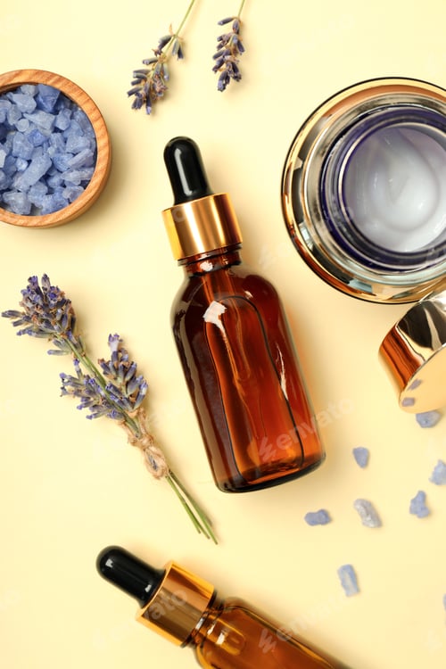 Preview: Cosmetic jar with cream, serum bottles, lavender and sea salt on light background, top view