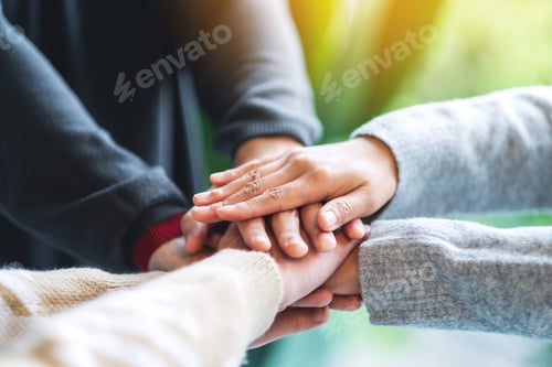 Preview: Closeup image of business team standing and joining their hands together in office