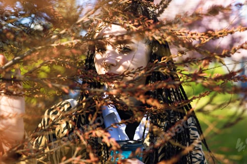 Preview: Young tender brunette girl with dreadlocks near herbal branch in front of her face. Portrait of a wo