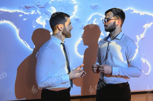 Preview: Two attractive young european businessmen on digital map blue background.