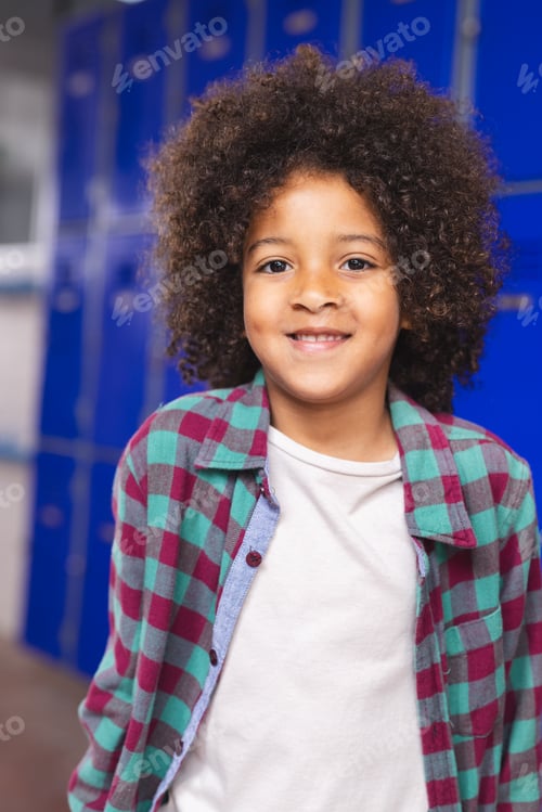 Preview: Biracial student smiling in front of blue background school lockers