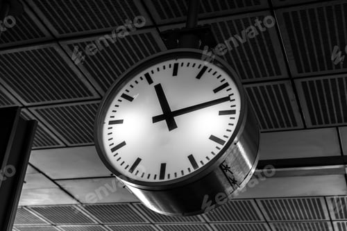 Preview: A black-and-white image of a round clock on a train station ceiling