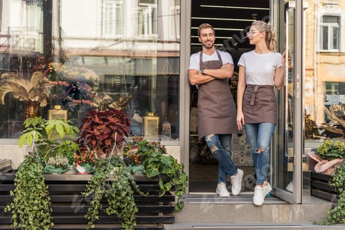 Preview: smiling coworkers standing in open door of flower shop