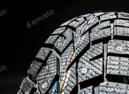 Preview: Close-up view of a winter tire showcasing tread patterns and metal studs