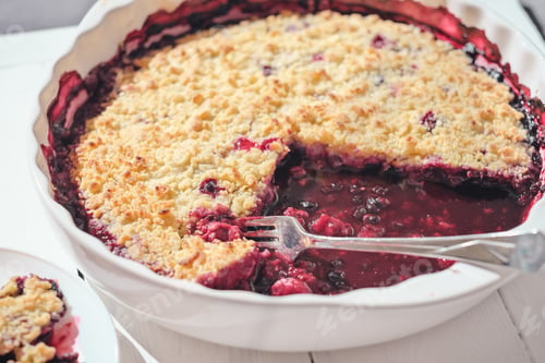 Preview: white ceramic baking dish with blueberry pie in it. fork left on a pie. home baking,