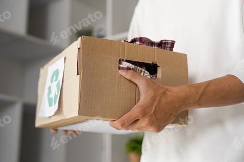 Preview: Young man carrying a box of recycled fabric, promoting eco-friendly