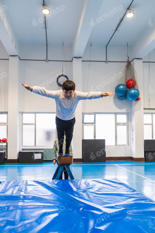 Preview: Young boy balancing on pommel horse during gymnastics class