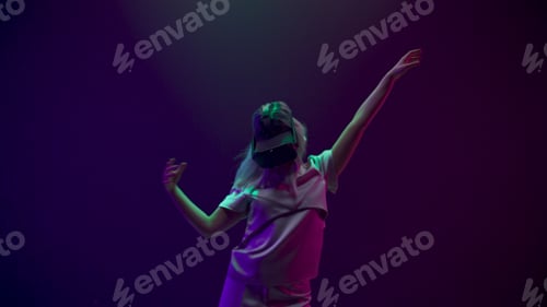 Preview: Blonde woman dancing in vr glasses at neon light.