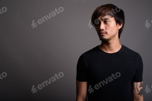 Preview: Young Asian man against gray background