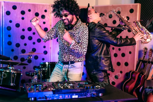 Preview: Young happy people playing music with dj mixer and saxophone in house studio