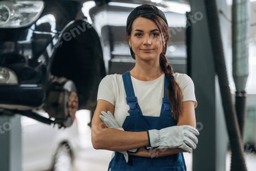 Preview: Arms crossed, standing and posing. Female mechanic is working in the modern car workshop