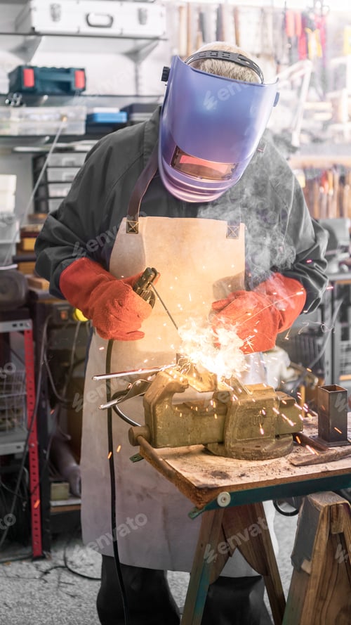 Preview: A man welder with safety helmet working with arc welding machine in the workshop