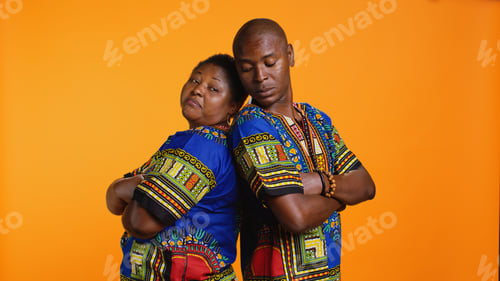 Preview: Serious proud ethnic couple standing back to back in studio
