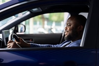 Preview: Smiling man enjoying car test drive in showroom