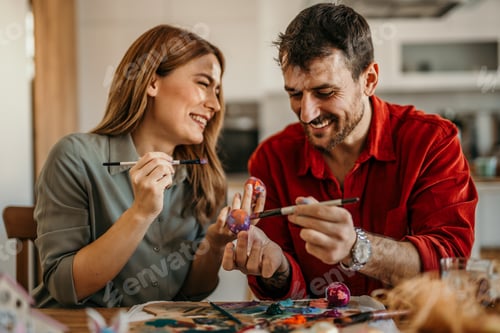 Preview: Couple painting colorful Easter eggs celebrating spring tradition