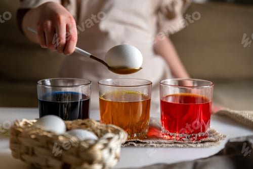 Preview: girl at home in the kitchen dyes eggs for Easter