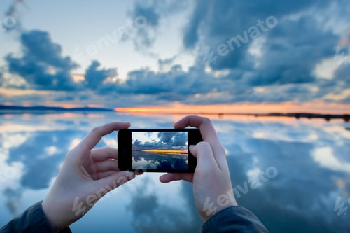 Preview: Person photographing reflections on lake with sunset, West Kirby, England, UK