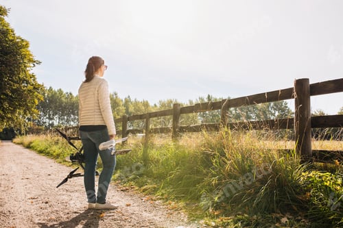 Preview: Woman standing on dirt road holding drone