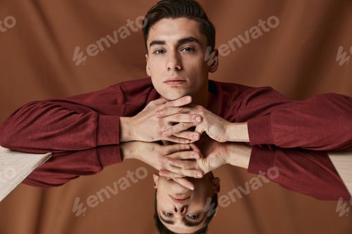 Preview: Handsome guy and brown shirt leaned on the glass on a fabric background