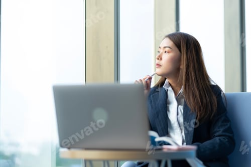 Preview: Businesswoman sitting and reading a book by the window of the office.