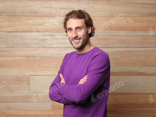 Preview: Handsome young man in warm sweater on wooden background