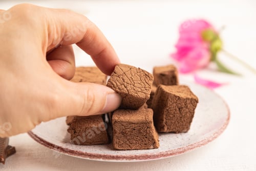 Preview: Chocolate marshmallow with cup of coffee with hand on white wooden. side view, selective focus