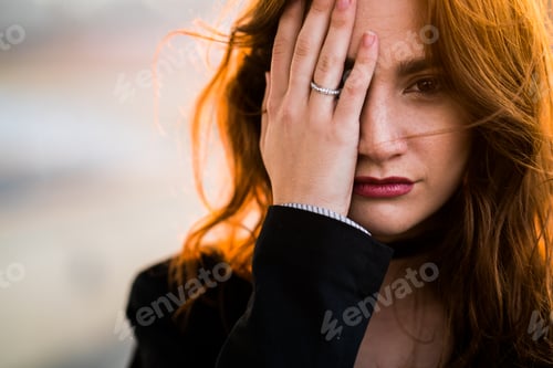 Preview: Young woman covering her face with her hand
