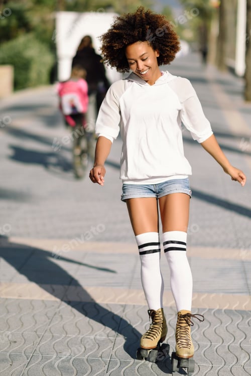 Preview: Black woman on roller skates rollerblading in beach promenade wi