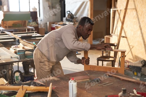 Preview: Black man building wooden furniture in carpentry workshop